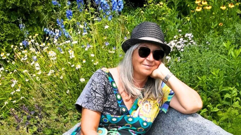 Petra Wild mit Sonnenhut auf einer Bank im Nepaltempel